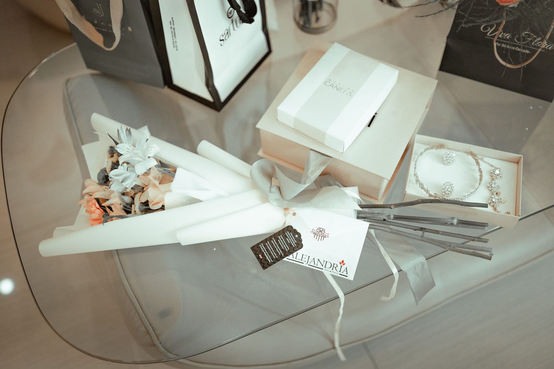 A wrapped gift box beside a delicate necklace on a linen surface