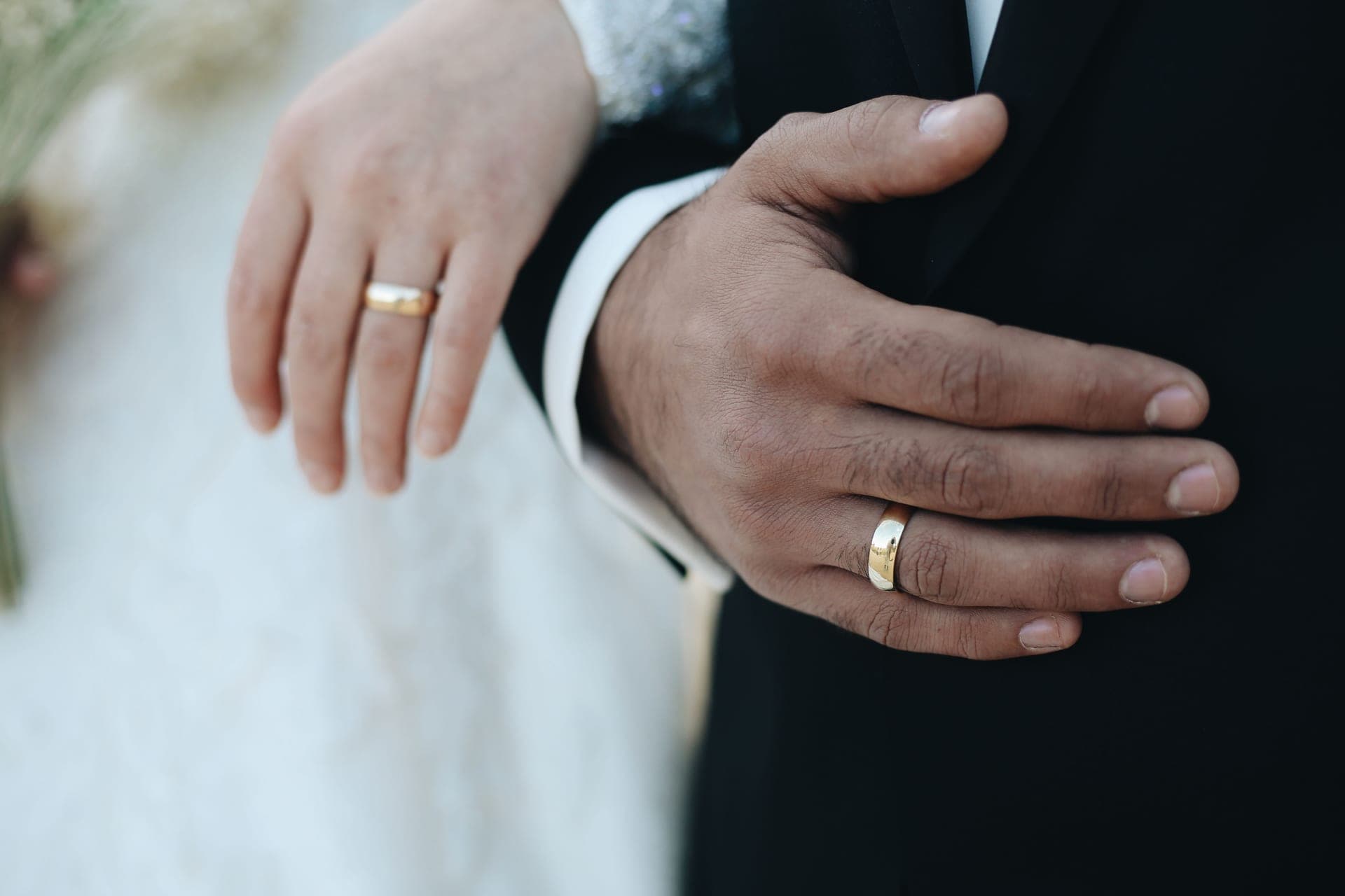 Two hands wearing wedding bands resting together