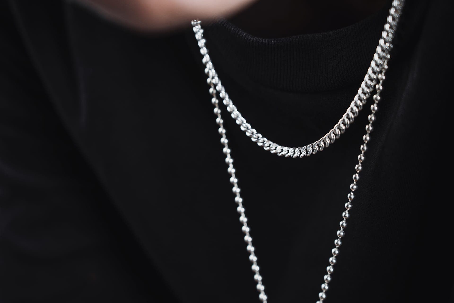 A men's steel chain necklace on a dark surface