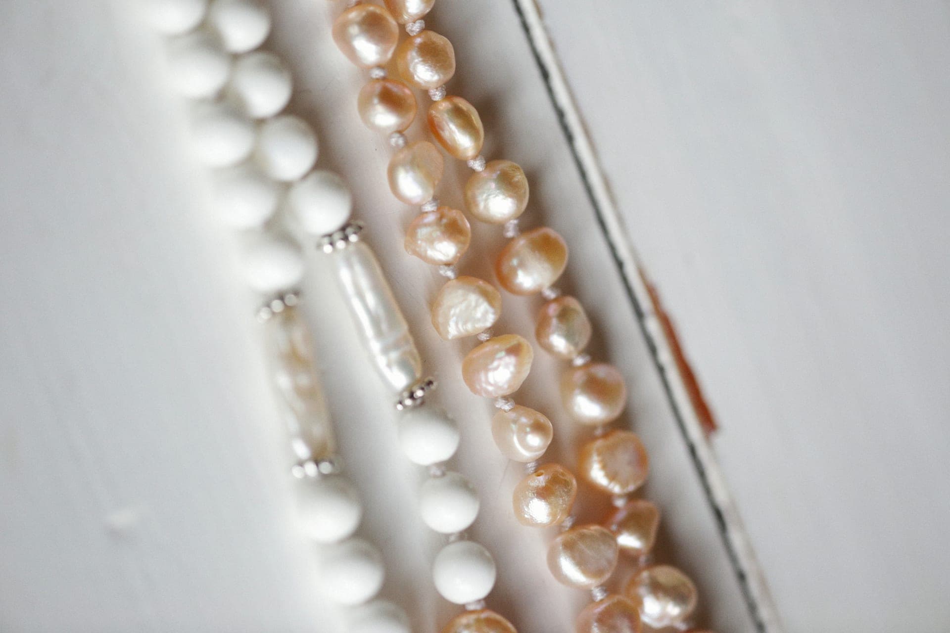 A strand of white pearls resting on a light fabric