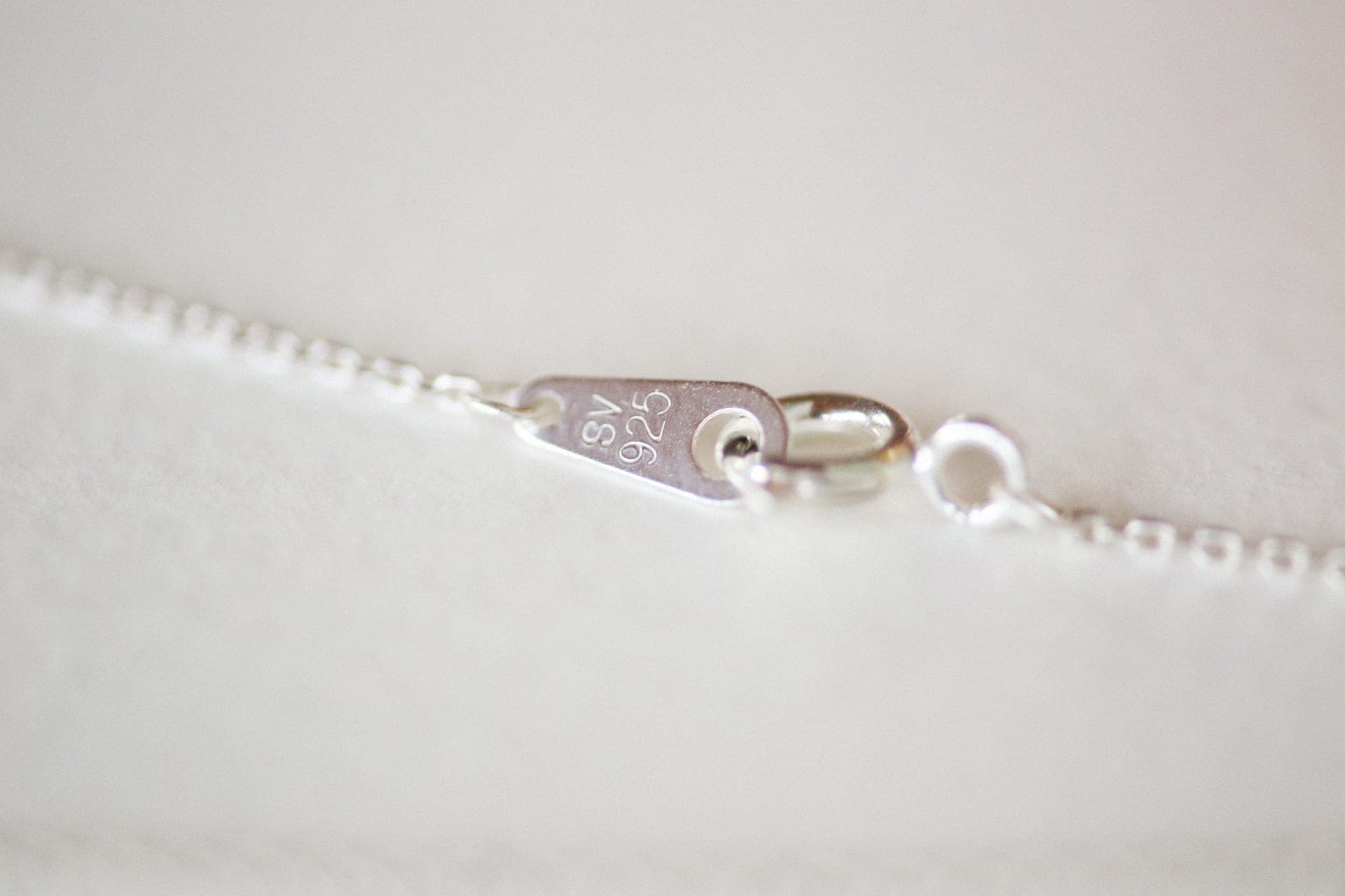 Silver chain necklace resting on a pale surface