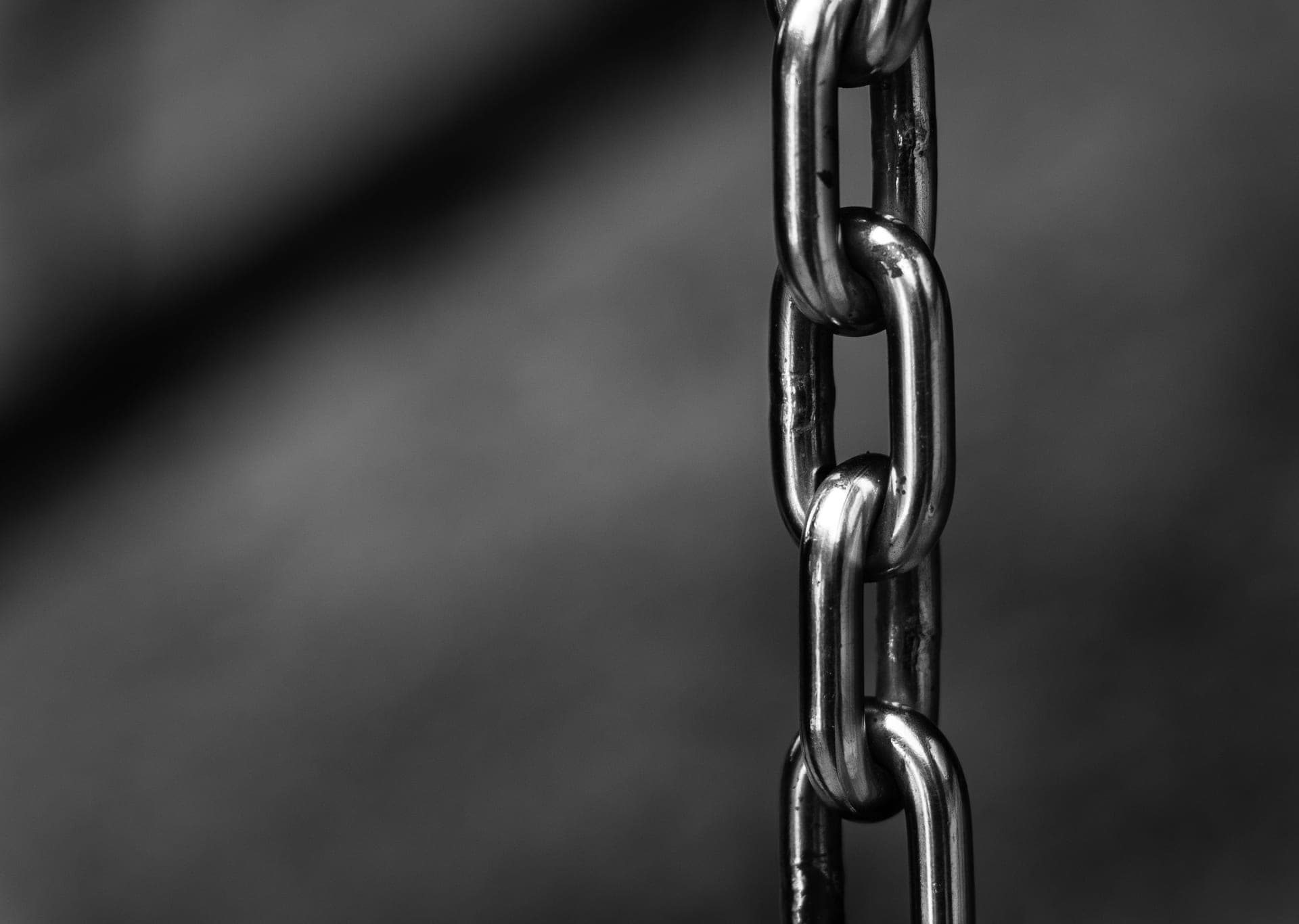 A polished stainless steel chain on a pale surface